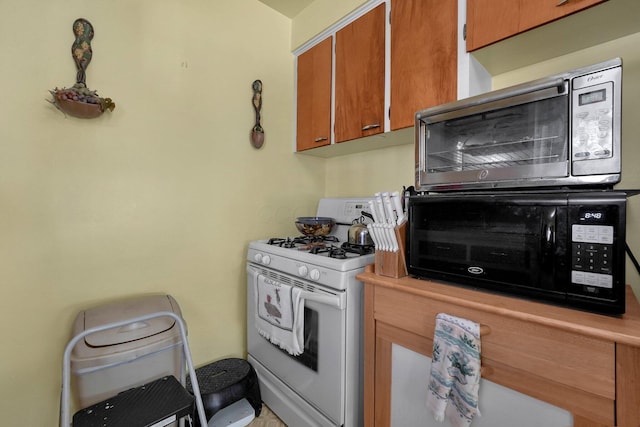 1920 S Champion Ave, Columbus, OH 43207 - kitchen featuring white range with gas stovetop, stainless steel microwave, black microwave, light countertops, and brown cabinets