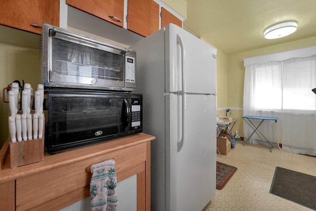 1920 S Champion Ave, Columbus, OH 43207 - kitchen featuring freestanding refrigerator, light flooring, brown cabinetry, stainless steel microwave, and baseboards