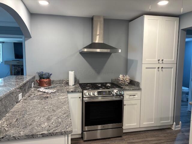 4367 Helena Ct, Springfield, OH 45503 - kitchen featuring stainless steel gas stove, wall chimney range hood, dark wood-style flooring, stone countertops, and white cabinetry