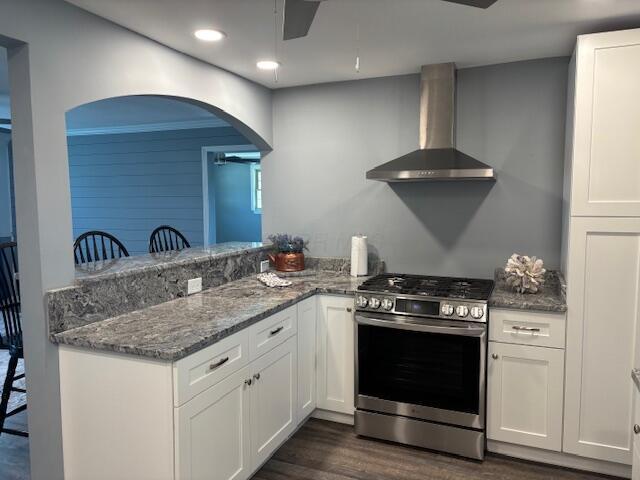 4367 Helena Ct, Springfield, OH 45503 - kitchen with gas stove, wall chimney exhaust hood, arched walkways, dark wood-style floors, and white cabinetry