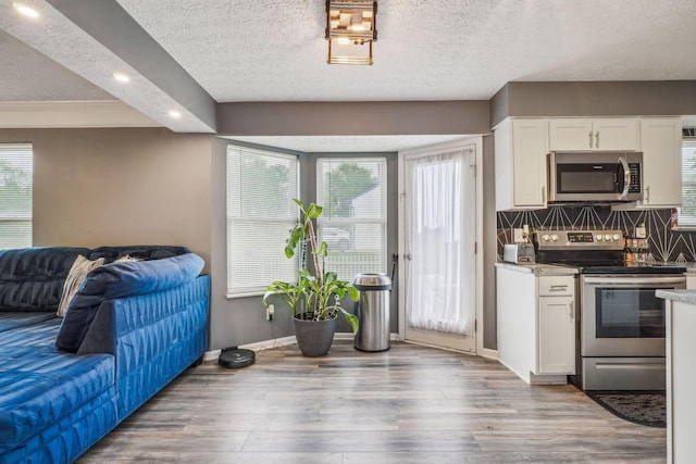 1536 Mulligan Ct, Reynoldsburg, OH 43068 - kitchen with stainless steel appliances, open floor plan, a textured ceiling, white cabinetry, and light wood-style floors