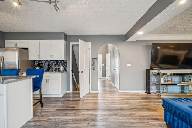 1536 Mulligan Ct, Reynoldsburg, OH 43068 - kitchen featuring freestanding refrigerator, arched walkways, a textured ceiling, baseboards, and white cabinetry