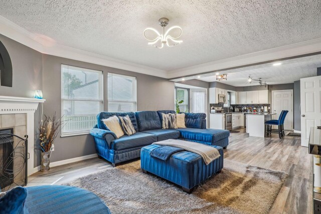 1536 Mulligan Ct, Reynoldsburg, OH 43068 - living area with crown molding, a chandelier, a textured ceiling, light wood-style flooring, and a tiled fireplace