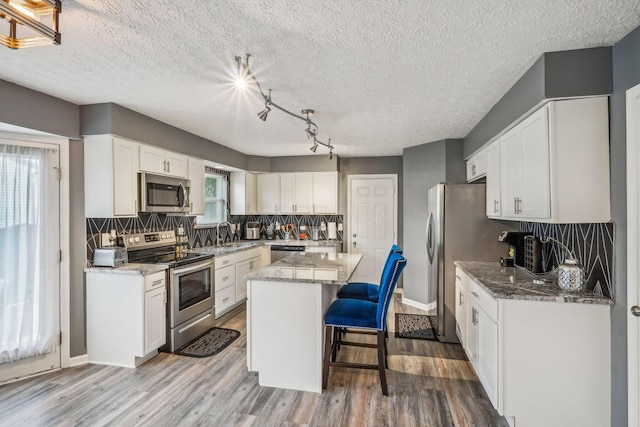 1536 Mulligan Ct, Reynoldsburg, OH 43068 - kitchen featuring appliances with stainless steel finishes, a center island, light stone countertops, backsplash, and white cabinets