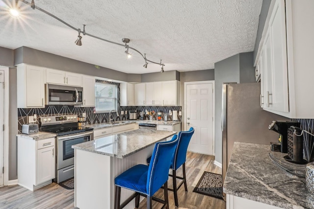 1536 Mulligan Ct, Reynoldsburg, OH 43068 - kitchen featuring stainless steel appliances, light wood-style flooring, a kitchen bar, a kitchen island, and backsplash