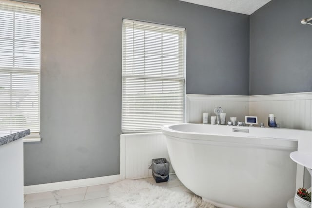 1536 Mulligan Ct, Reynoldsburg, OH 43068 - bathroom featuring a freestanding bath, marble finish floors, plenty of natural light, and a wainscoted wall