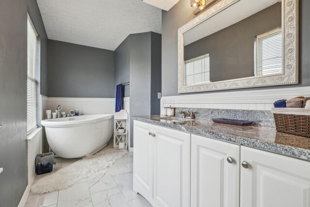 1536 Mulligan Ct, Reynoldsburg, OH 43068 - full bathroom featuring marble look tile flooring, vanity, a freestanding tub, healthy amount of natural light, and a wainscoted wall