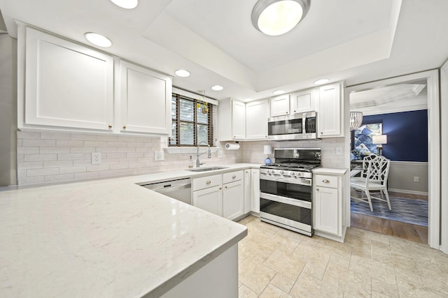 1009 Tall Tree Ct, Westerville, OH 43081 - kitchen with stainless steel appliances, a sink, white cabinets, backsplash, and a raised ceiling