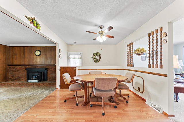 4818 Manitoba Rd, Columbus, OH 43229 - dining room with wood finished floors, a ceiling fan, a textured ceiling, a wood stove, and wooden walls