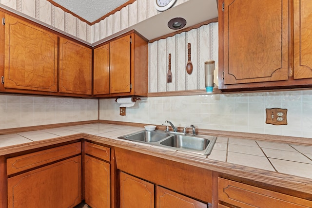 4818 Manitoba Rd, Columbus, OH 43229 - kitchen with tile countertops, a sink, brown cabinets, and decorative backsplash