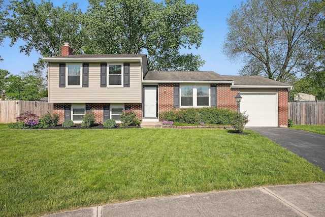 651 Dovalon Pl, Galloway, OH 43119 - split level home featuring asphalt driveway, a chimney, an attached garage, and brick siding