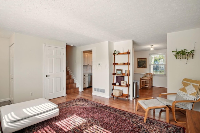 651 Dovalon Pl, Galloway, OH 43119 - living area with wood finished floors, a textured ceiling, stairs, and baseboards