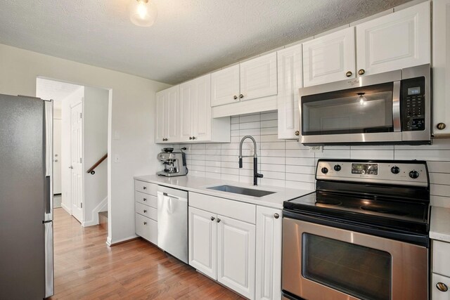 651 Dovalon Pl, Galloway, OH 43119 - kitchen featuring stainless steel appliances, a sink, light countertops, light wood-style floors, and decorative backsplash