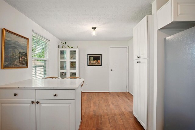 651 Dovalon Pl, Galloway, OH 43119 - kitchen featuring light wood-style flooring, a textured ceiling, light countertops, and white cabinetry