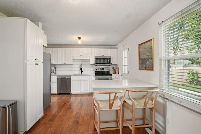 651 Dovalon Pl, Galloway, OH 43119 - kitchen featuring appliances with stainless steel finishes, a sink, white cabinetry, light countertops, and dark wood-style flooring