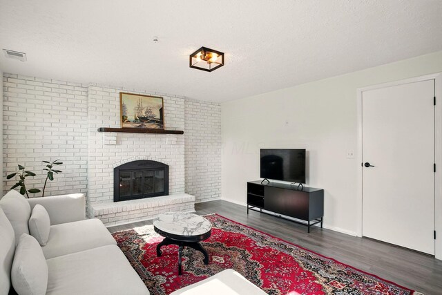 651 Dovalon Pl, Galloway, OH 43119 - living room with wood finished floors, a brick fireplace, baseboards, a textured ceiling, and brick wall