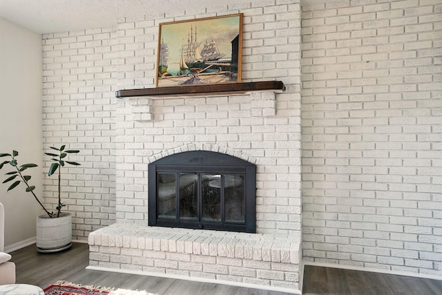 651 Dovalon Pl, Galloway, OH 43119 - detailed view of wood finished floors, a brick fireplace, baseboards, and a textured ceiling