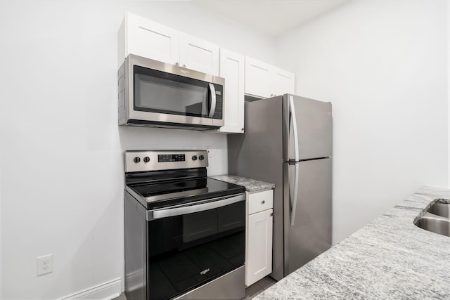 848-850 Carpenter St, Columbus, OH 43206 - kitchen featuring appliances with stainless steel finishes, white cabinets, light stone countertops, and baseboards