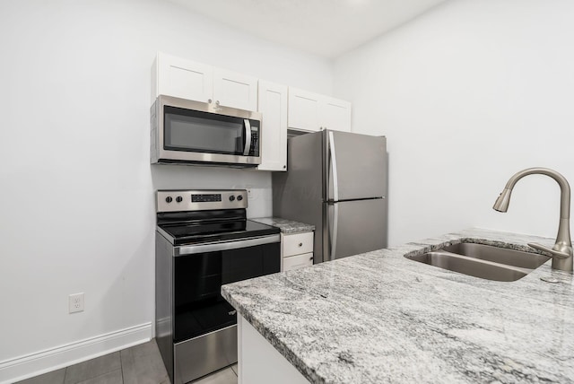 848-850 Carpenter St, Columbus, OH 43206 - kitchen featuring stainless steel appliances, a sink, white cabinets, light stone counters, and baseboards