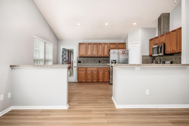 1472 Tall Meadows Dr, Columbus, OH 43223 - kitchen featuring stainless steel appliances, decorative backsplash, light wood-type flooring, lofted ceiling, and brown cabinetry