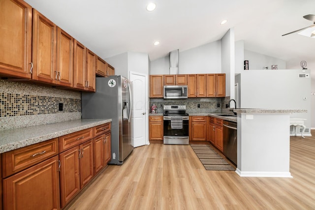 1472 Tall Meadows Dr, Columbus, OH 43223 - kitchen featuring stainless steel appliances, a sink, light wood-style floors, brown cabinetry, and lofted ceiling