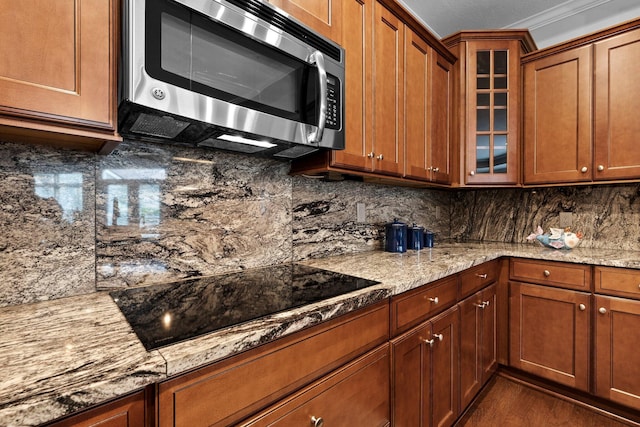 5568 Lexington Dr, Hilliard, OH 43026 - kitchen featuring stainless steel microwave, black electric cooktop, glass insert cabinets, and decorative backsplash