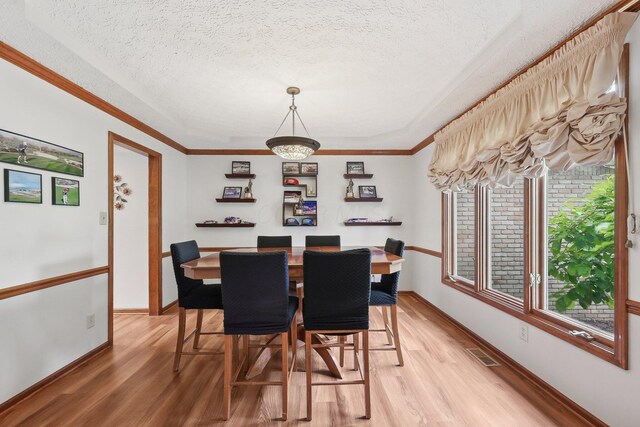 8628 N Spring Ct, Pickerington, OH 43147 - dining room featuring light wood finished floors, a textured ceiling, baseboards, and ornamental molding