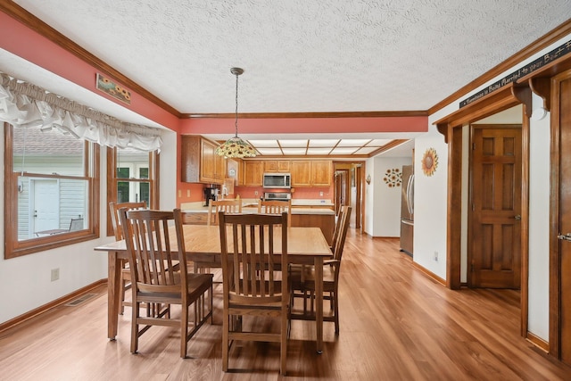 8628 N Spring Ct, Pickerington, OH 43147 - dining area featuring crown molding, light wood-type flooring, baseboards, and a textured ceiling