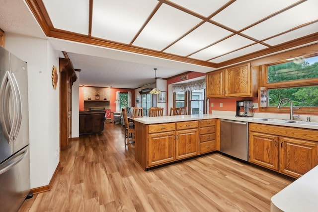 8628 N Spring Ct, Pickerington, OH 43147 - kitchen featuring appliances with stainless steel finishes, brown cabinets, a peninsula, light wood-style floors, and light countertops