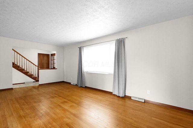 11831 Woodbridge Ln NW, Baltimore, OH 43105 - unfurnished room featuring light wood finished floors, stairs, a textured ceiling, and baseboards
