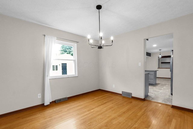 11831 Woodbridge Ln NW, Baltimore, OH 43105 - unfurnished room with a chandelier, light wood-style flooring, and baseboards