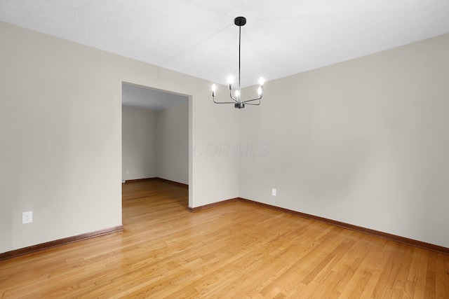 11831 Woodbridge Ln NW, Baltimore, OH 43105 - spare room with a chandelier, light wood-type flooring, and baseboards