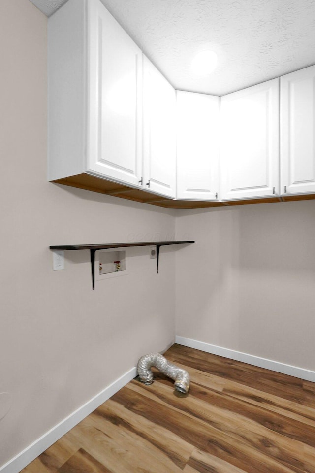 11831 Woodbridge Ln NW, Baltimore, OH 43105 - laundry area featuring cabinet space, wood finished floors, baseboards, and hookup for a washing machine