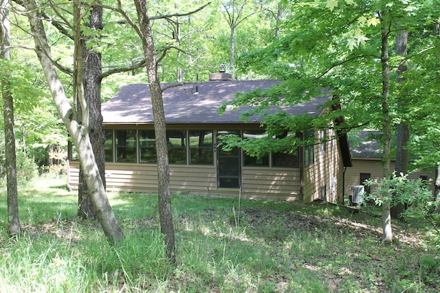 387 Mohican Ln, Sugar Grove, OH 43155 - view of front facade with a chimney, roof with shingles, a sunroom, and cooling unit
