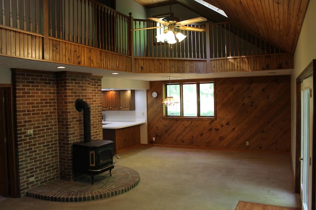 387 Mohican Ln, Sugar Grove, OH 43155 - unfurnished living room featuring wood walls, high vaulted ceiling, a wood stove, light colored carpet, and a ceiling fan