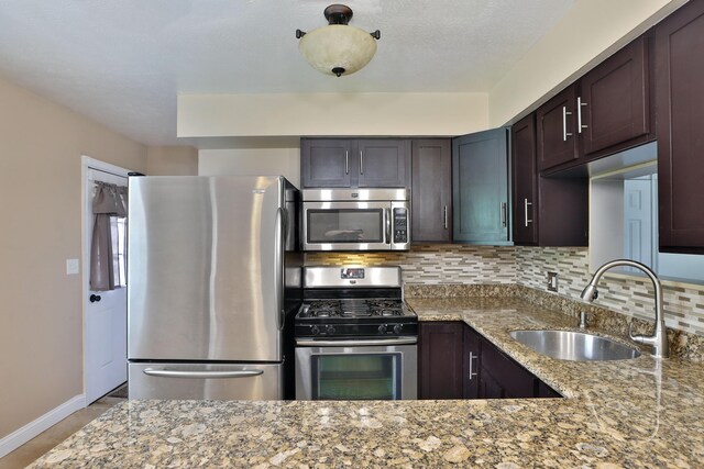 6219 Ambleside Dr, Columbus, OH 43229 - kitchen with appliances with stainless steel finishes, a sink, light stone countertops, dark brown cabinets, and backsplash