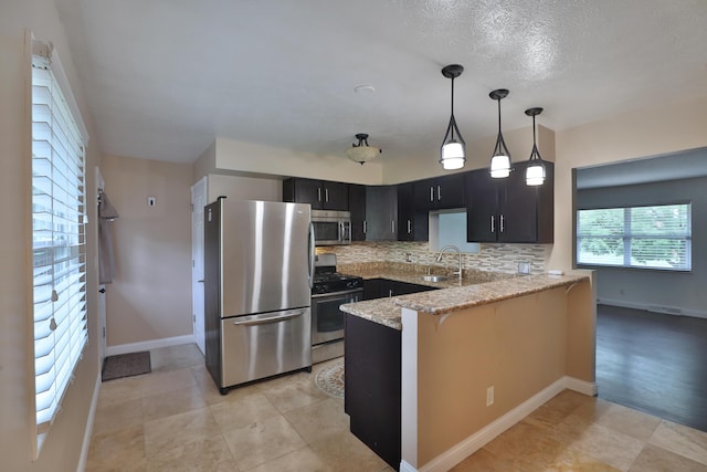 6219 Ambleside Dr, Columbus, OH 43229 - kitchen with stainless steel appliances, a peninsula, a sink, decorative backsplash, and light stone countertops