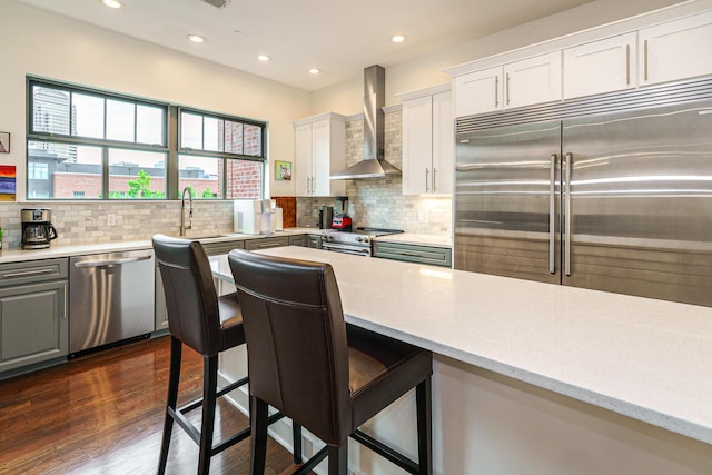 251 Daniel Burnham Sq Unit 703, Columbus, OH 43215 - kitchen featuring wall chimney range hood, appliances with stainless steel finishes, a sink, white cabinets, and backsplash