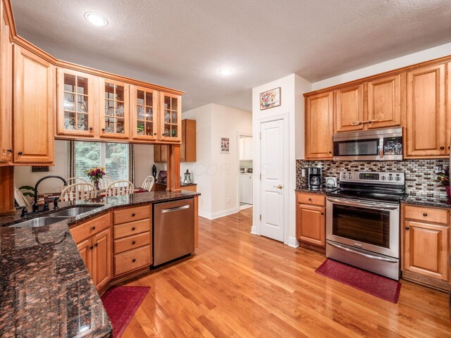 8171 Campden Lakes Blvd, Dublin, OH 43016 - kitchen with stainless steel appliances, a sink, light wood finished floors, backsplash, and glass insert cabinets