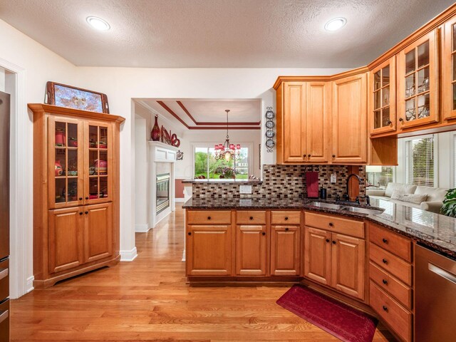 8171 Campden Lakes Blvd, Dublin, OH 43016 - kitchen featuring a sink, a peninsula, light wood-style flooring, stainless steel dishwasher, and decorative backsplash