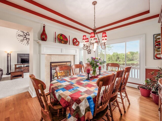 8171 Campden Lakes Blvd, Dublin, OH 43016 - dining room with a chandelier, light wood-style floors, a tile fireplace, a raised ceiling, and crown molding