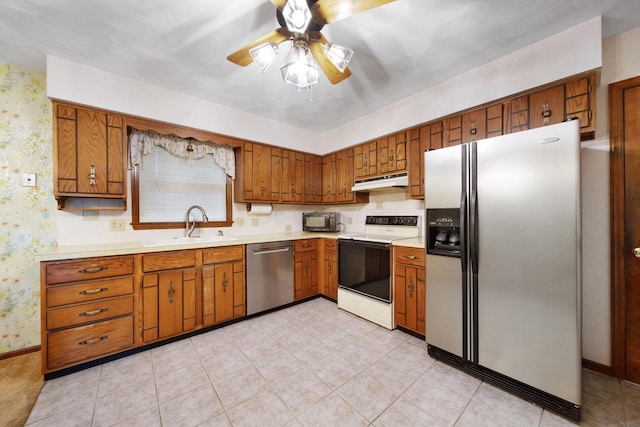 2580 Applewood Ln NE, Lancaster, OH 43130 - kitchen featuring appliances with stainless steel finishes, under cabinet range hood, brown cabinets, wallpapered walls, and light countertops