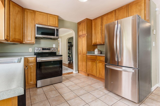 2008 N Edgemont Rd, Upper Arlington, OH 43212 - kitchen featuring stainless steel appliances, arched walkways, light countertops, and light tile patterned floors