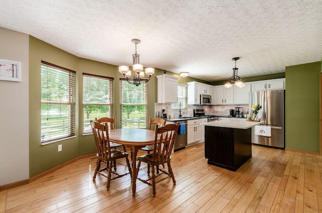 6249 Corley Dr, Dublin, OH 43016 - dining area featuring a chandelier, baseboards, light wood-style flooring, and a textured ceiling