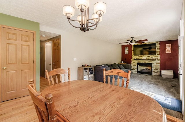 6249 Corley Dr, Dublin, OH 43016 - dining space featuring ceiling fan, a chandelier, a fireplace, a textured ceiling, and light wood-style flooring