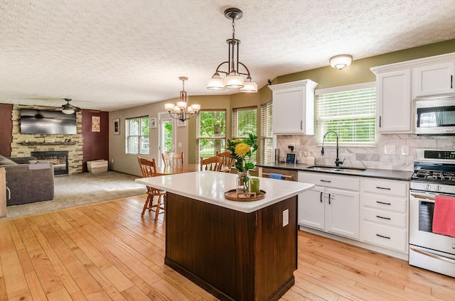6249 Corley Dr, Dublin, OH 43016 - kitchen featuring stainless steel appliances, a sink, a stone fireplace, a center island, and open floor plan