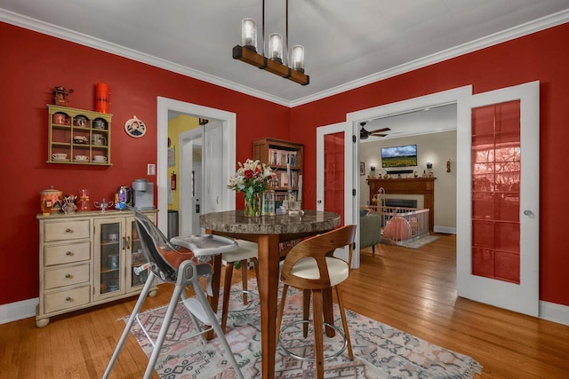 297 S James Rd, Columbus, OH 43213 - dining room featuring light wood-style flooring, crown molding, a fireplace, baseboards, and ceiling fan