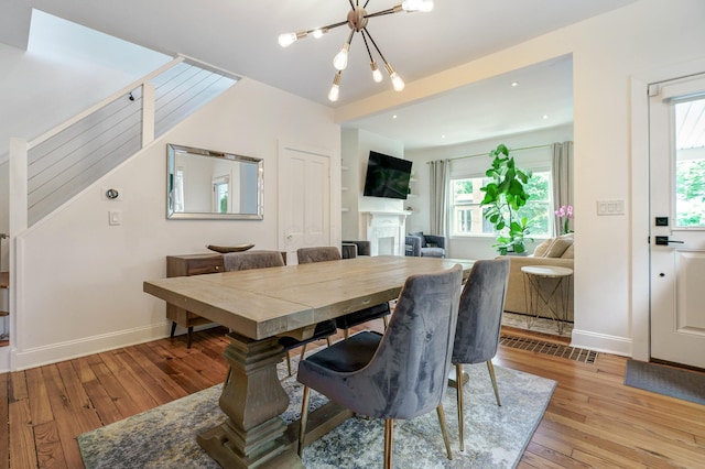 432 E Kossuth St, Columbus, OH 43206 - dining area with a chandelier, baseboards, light wood-style floors, and a fireplace