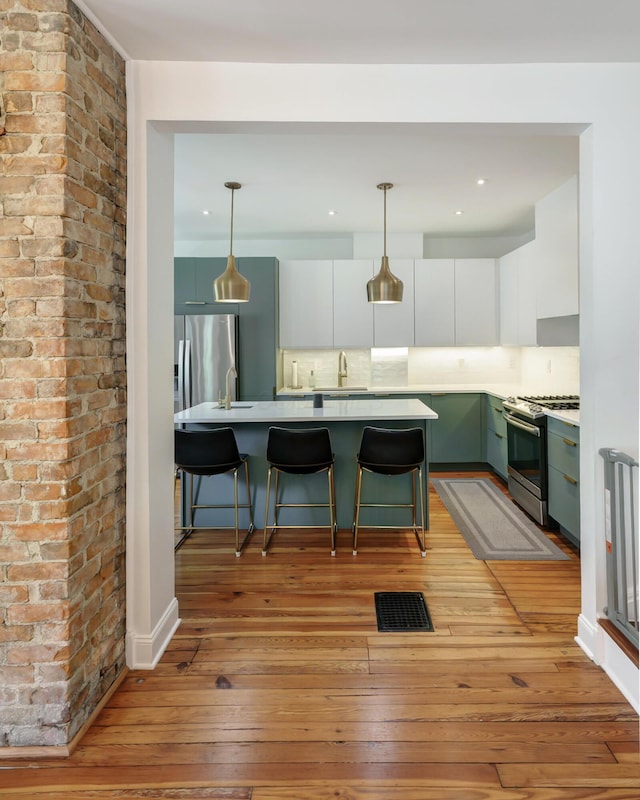 432 E Kossuth St, Columbus, OH 43206 - kitchen with appliances with stainless steel finishes, light wood-style flooring, a sink, light countertops, and white cabinetry