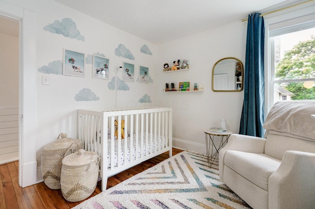 432 E Kossuth St, Columbus, OH 43206 - bedroom with wood finished floors, a crib, and baseboards